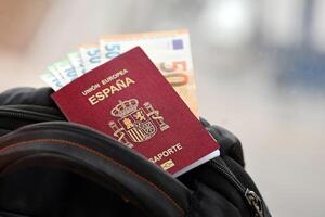 rood Spaans paspoort van Europese unie met geld en vliegmaatschappij kaartjes Aan toeristisch rugzak foto