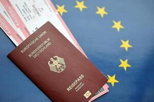 rood Duitse paspoort van Europese unie en luchtvaartmaatschappijen kaartjes Aan blauw vlag achtergrond dichtbij omhoog foto