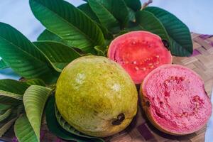 guava geïsoleerd. verzameling van rood vleesgeworden guava fruit met geelachtig groen huid en bladeren geïsoleerd Aan een wit achtergrond met bamboe matten. foto