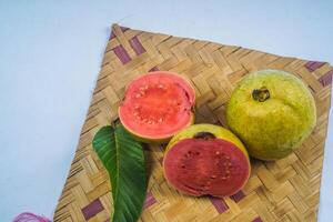 guava geïsoleerd. verzameling van rood vleesgeworden guava fruit met geelachtig groen huid en bladeren geïsoleerd Aan een wit achtergrond met bamboe matten. foto