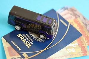 blauw braziliaans paspoort met geld en klein bus Aan blauw achtergrond dichtbij omhoog foto