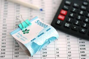 bedrijf berekeningen met Indonesisch roepia geld rekeningen en rekenmachine met pen Aan kantoor tafel foto