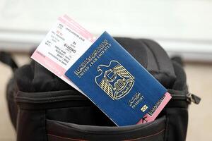 blauw Verenigde Arabisch emiraten paspoort met vliegmaatschappij kaartjes Aan toeristisch rugzak foto
