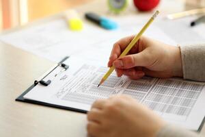 vrouw leerling handen testen in oefening en nemen vullen in tentamen papier vel met potlood Bij school- test foto