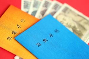 Japans pensioen verzekering boekjes Aan tafel met yen geld rekeningen. blauw en oranje boeken foto