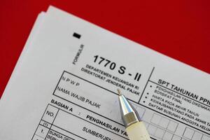 Indonesisch belasting het formulier 1770 s - 2 individu inkomen belasting terugkeer en pen Aan tafel foto