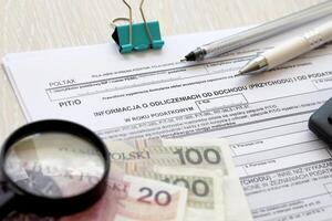 informatie over inhoudingen van inkomen en belasting, pit-o het formulier Aan accountant tafel met pen en Pools zloty geld rekeningen foto