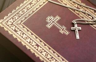 zilver ketting met kruisbeeld kruis Aan christen heilig Bijbel boek Aan zwart houten tafel. vragen zegeningen van god met de macht van heiligheid, welke brengt geluk foto