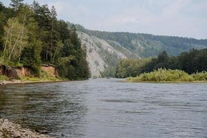 de berg rots is zichtbaar bovenstaand de water, de rivier- gedurende de regenachtig seizoen, de volstromend bed van de berg rivier, de mooi landschap in de taiga, de modderstroom bossen van Siberië. foto