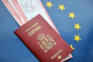 rood Spaans paspoort van Europese unie met vliegmaatschappij kaartjes Aan blauw achtergrond dichtbij omhoog foto