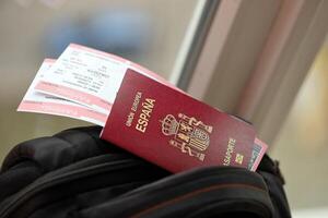 rood Spaans paspoort van Europese unie met vliegmaatschappij kaartjes Aan toeristisch rugzak foto