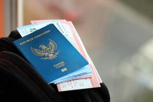 blauw republiek Indonesië paspoort met geld en vliegmaatschappij kaartjes Aan toeristisch rugzak foto