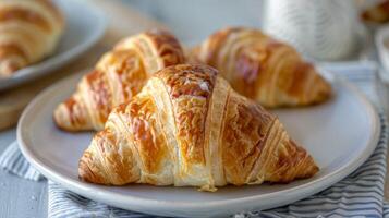 gouden croissant Aan een bord met vlokkig lagen, een heerlijk Frans gebakje voor ontbijt foto