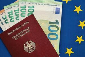 rood Duitse paspoort van Europese unie en geld Aan blauw vlag achtergrond dichtbij omhoog foto