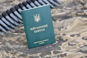 oekraïens leger ID kaart Aan kleding stof met structuur van korrelig camouflage. kleding met camo patroon in grijs, bruin en groen pixel vormen met oekraïens leger persoonlijk token foto