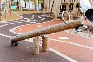 houten schommel, log met twee stoelen voor kinderen, speelplaats voor kinderen, stad park, buitenshuis sport. rubber bijhouden voor rennen. foto