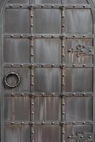 een oud metaal deur, nagemaakt poorten, klinknagels Aan de facade van een gietijzer deur, een ronde omgaan met naar Open de deur, de structuur van oud ijzer. foto