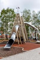 een groot sport- Speel complex voor kinderen in de Open lucht, een kinderen speelplaats gemaakt van hout in de stad park, een metaal schuiven, een piramide van logboeken, een attractie voor kinderen. foto