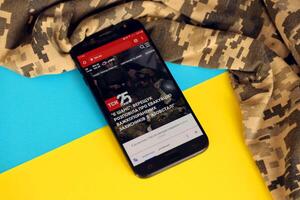 kiev, Oekraïne - 4 kunnen, 2023 tsn oekraïens nieuws portaal Aan smartphone scherm met oekraïens vlag en camouflage kleding stof foto