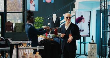 beroemd couturier geven bestellen naar op te slaan assistent naar helpen met vinden een stropdas voor zijn Afrikaanse Amerikaans cliënt, ervaren senior kleermaker in. mode ontwerper boodschappen doen voor luxe accessoires. camera b. foto