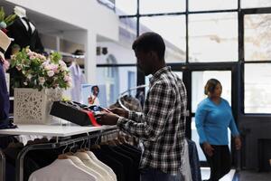 Afrikaanse Amerikaans klant op zoek Bij plank vol met accessoires, controle modieus riem in modern boetiek. elegant Mens boodschappen doen voor gewoontjes slijtage in kleding op te slaan. mode concept foto