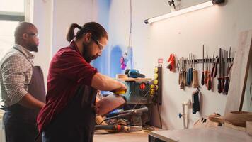 timmerman aan het doen laatste accenten Aan stuk van hout voordat gebruik makend van het voor meubilair bijeenkomst, schuren het met schuurpapier. houtbewerking deskundige aan het doen houtbewerking werkwijze Aan timmerhout blok, vaststelling schade, camera b foto