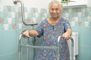 Aziatisch ouderen vrouw gebruik badkamer omgaan met veiligheid in toilet, gezond sterk medisch concept. foto