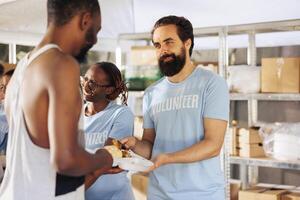 portret van mannetje liefdadigheid arbeider verspreiden van vrij voedsel naar de behoeftig en dakloos mensen. Bij non-profit voedsel drijfveer, vriendelijk Mens vrijwilliger sharing maaltijd pakket naar de hongerig en minder bevoorrecht. foto