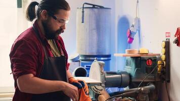 timmerman in houtbewerking winkel zetten Aan bescherming handschoenen voordat in elkaar zetten meubilair. meubelmaker vervelend veiligheid uitrusting voordat beginnend werk naar vermijden verwondingen, camera een foto