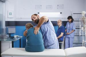 gecertificeerd kinesiotherapie beoefenaar assists ouderen geduldig met spier uitrekken en spinal druk Verlichting. medisch assistent het verstrekken van bijstand met terug pijn gedurende fysiek therapie. foto