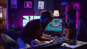 blij artiest spelen piano toetsenbord en opname deuntjes voor menging en beheersen sessie, genieten van midi controleur prestatie in huis studio. energiek muziek- producent creëren soundtracks. camera b. foto