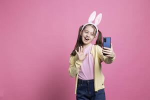 blij jong meisje golvend Bij camera Aan video-oproep verbinding, pratend naar haar school- vrienden gebruik makend van online videoconferentie. weinig glimlachen preteen hebben een afgelegen gesprek Aan smartphone app. foto