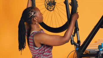 vrouw aan het doen fiets onderhoud in studio achtergrond atelier winkel, zoeken plaatsvervanger voor defecte wiel. technicus vaststelling defect fiets banden en onderhoud beschadigd achterzijde derailleur foto