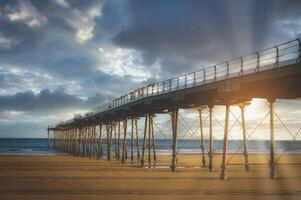 de pier Bij zonsondergang in zoutverbranding door de zee, noorden yorkshire, uk foto