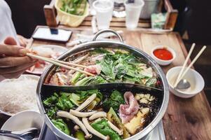 heet pot met Doorzichtig soep, varkensvlees, vis, groenten, geblancheerd in heet bouillon en gedoopt in een verscheidenheid van sauzen. foto