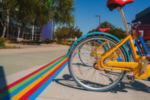 levendig gekleurde fiets geparkeerd Aan kleurrijk pad met modern gebouw in achtergrond foto