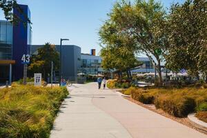 modern campus tafereel met gebouw 43, voetganger brug, en werkzaamheid in zonnig instelling foto