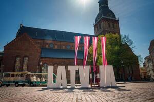 zonnig dag in oud stad- Riga met Letland teken en trolley bus foto