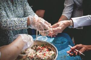 dakloos mensen bereiken uit naar te ontvangen vrij voedsel dat vrijwilligers brengen. naar helpen verlichten honger foto