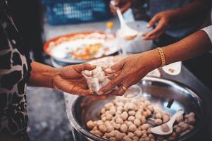vrijwilligers portie heet maaltijden naar hongerig migranten humanitair steun concept. foto