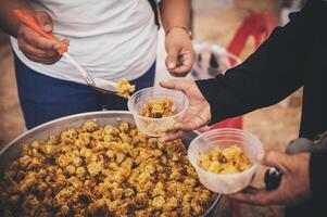 vrijwilligers verdelen gemakkelijk maaltijden naar de arm Bij de vrij voedsel keuken. foto