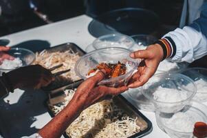 vrijwilligers aanbod vrij voedsel naar de arm. de concept van voedsel delen. foto