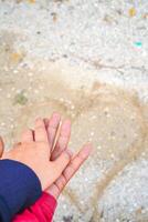 de handen van een paar Holding handen tegen de achtergrond van strand zand. foto