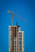 een kraan gebouw een wolkenkrabber tegen een blauw lucht. foto