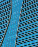 fragment van een modern kantoor gebouw. abstract meetkundig achtergrond. een deel van een wolkenkrabber met glas ramen. foto