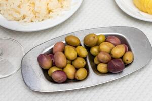 een rustiek alentejo tafel met een kom van groen olijven en een bord van traditioneel kaas. zijn een gemakkelijk nog uitnodigend instelling, reflecterend de warmte en authenticiteit van Portugees keuken. foto