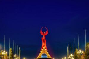 Oezbekistan, Tasjkent - januari 4, 2023 verlichte monument van onafhankelijkheid in de het formulier van een stele met een humo vogel in de nieuw Oezbekistan park Bij nacht. foto