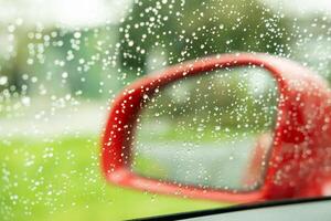 rood buitenkant spiegel van een auto in de regen foto