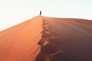 vrouw silhouet genieten van zandduinen in de woestijn in zonsondergang blauwe uur alleen. reizen levensstijl en wellness-concept. filmische reislustachtergrond foto