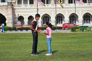 Kuala lomp, Maleisië Aan mei 21, 2023. een ouder broer en een jonger zus zijn spelen Aan de dataran merdeka veld- foto